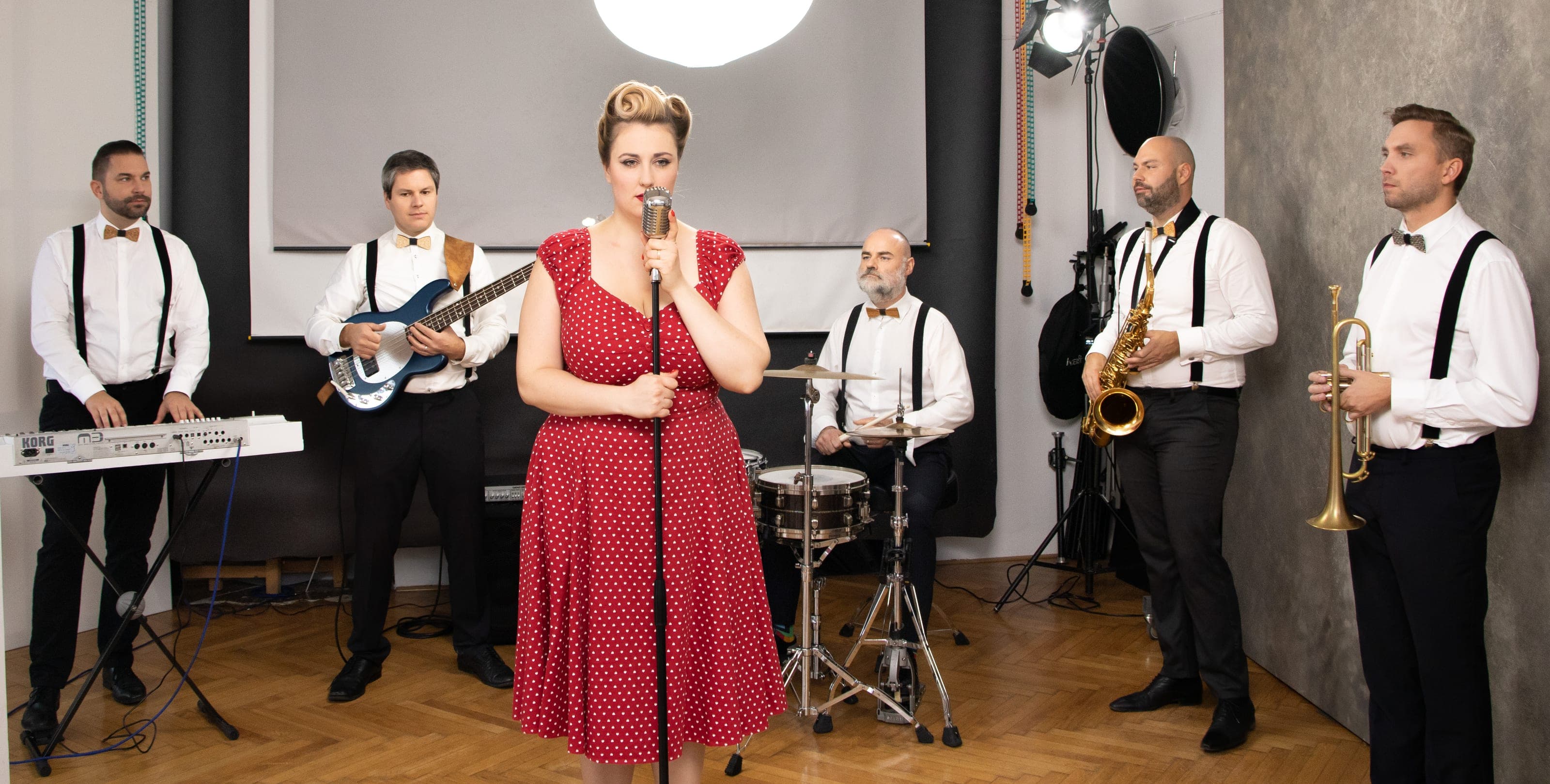 ROURA in a formal line-up with a red dress, white shirts and brass section